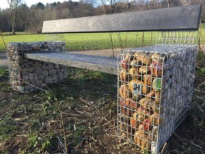 A gabion basket style bench in Witton Park, Blackburn, on the banks of the River Darwen. The pebbles within the gabion basket arms were decorated with river wildlife. 